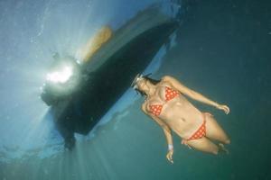 skön flicka simning under en fartyg foto