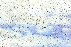 närbild och beskära regn släppa på glas och suddigt ljus blå bakgrund foto
