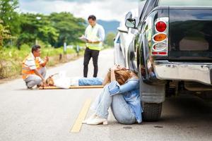en ung kvinna sitter gråt Nästa till de bil hon kraschade in i någon på de väg. foto