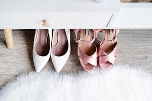 närbild av elegant hög häl skor stående under feminin klä på sig tabell foto