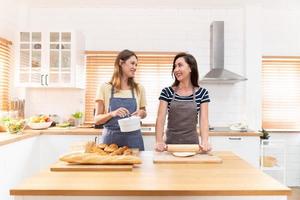 två caucasian kvinnor matlagning pizza tillsammans i de kök. de begrepp av hemlagad mat och HBTQ relationer. familj och mångfald begrepp. HBTQ. foto