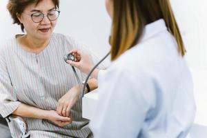 ung läkare använder stetoskop för att undersöka senior patient hjärta foto