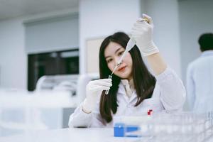 ung medicinsk forskare som arbetar i medicinskt laboratorium, ung kvinnlig forskare som använder autopipett för att överföra prov foto