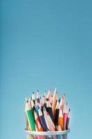 färgrik pennor i en metall burk på en blå bakgrund. foto