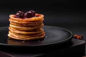 utsökt färsk pannkakor med bär sylt på en svart keramisk tallrik foto