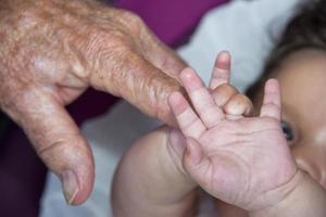 gammal pensionerad man händer innehav nyfödd spädbarn ett foto