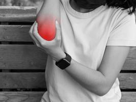ung kvinna med gemensam smärta på en grå bakgrund, svart och vit bild med röd prickar. foto