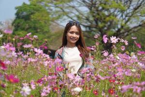 Lycklig asiatisk kvinna i kosmos blomma trädgård foto