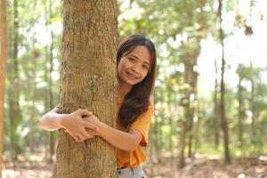 begrepp av sparande de värld asiatisk kvinna kramas en träd foto