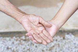 närbild av gammal och ung innehav händer. medelålders mammas rynkig händer innehav ung döttrar, en tusenåriga kvinna stödjande mogna mamma, som visar vård, och kärlek. Stöd för de äldre begrepp. foto