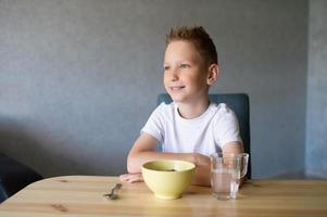 söt pojke äter en torr frukost på Hem och ler foto
