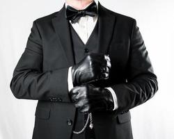 porträtt av herre i mörk kostym och läder handskar på vit bakgrund. årgång mode och retro stil. formell kväll klädsel. foto