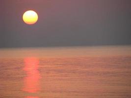 de ljus orange kväll Sol i de lugna hav. foto