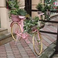 gammal rosa cykel utrustad med korg av blommor dekoration foto