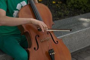 detalj av en man spelar de trä- cello gnuggning de strängar med de rosett till skaffa sig de anteckningar av en klassisk musik bit. foto