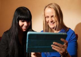 två unga kvinnor som använder en tablett foto