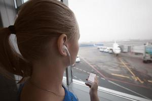 kvinna i hörlurar som tittar på flygplatsen foto