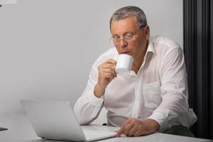 affärsman som dricker kaffe medan han arbetar på kontoret foto
