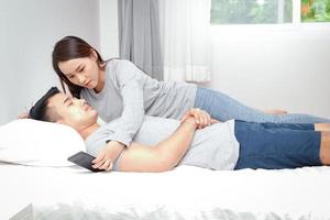 asiatisk par lägga i säng i de sovrum. de kvinna gör inte förtroende de man, i hemlighet öppnas till kolla upp hans telefon information. familj begrepp foto