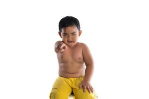 liten asiatisk pojke med arg förvirrad uttryck i ansiktssammanträde isolerad på vit bakgrund foto