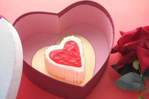 ovanifrån av hjärtformad tårta, presentask och rosblomma på röd bakgrund foto