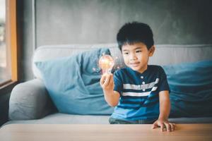 fyra år gammal asiatisk pojke innehav ljus lökar, idéer av ny idéer med innovativ teknologi och kreativitet. begrepp kreativitet med lökar den där glans glitter. foto