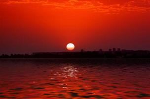 solnedgång över stadens silhuett vid vattnet