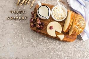 de fest av de ger av de Tora. mejeri Produkter, bröd, vindruvor. de begrepp av de jewish Semester. grå bakgrund med brev - Lycklig shavuot. foto