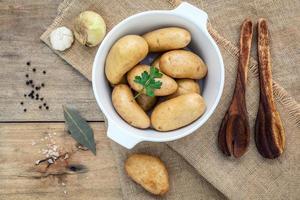 färska ekologiska potatisar i en vit keramisk skål med örter foto