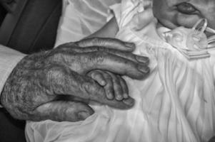 gammal pensionerad man händer innehav nyfödd spädbarn ett foto