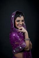 porträtt av leende skön indisk flicka bär traditionell lila kläder foto