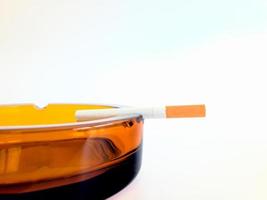 obelyst cigarett på ett askfat foto