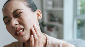 olycklig asiatisk kvinna lidande från smärta i de tand foto