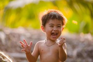 asiatisk pojke som ler och leker med vatten foto