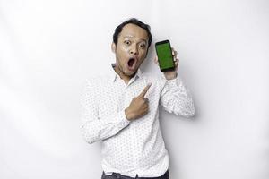 chockade asiatisk man bär en vit skjorta och som visar grön skärm på hans telefon, isolerat förbi vit bakgrund foto