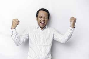 en ung asiatisk man med en Lycklig framgångsrik uttryck bär vit skjorta isolerat förbi vit bakgrund foto