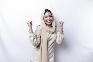 en ung asiatisk muslim kvinna med en Lycklig framgångsrik uttryck bär en hijab isolerat förbi vit bakgrund foto