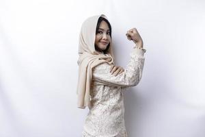 upphetsad asiatisk muslim kvinna bär en hijab som visar stark gest förbi lyft henne vapen och muskler leende stolt foto