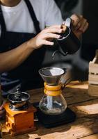 professionell Barista framställning kaffe använder sig av chemex Häll i över kaffe tillverkare och droppa vattenkokare. alternativ sätt av bryggning kaffe. kaffe affär begrepp. foto