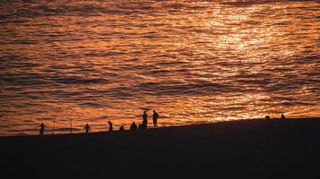 människor på stranden under solnedgången foto