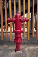 en röd brand brandpost med två vapen på både sidor. gyllene staket bakgrund. stå rör brandpost utomhus. foto