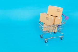 papperslådor i en vagn på en blå bakgrund. online shopping eller e-handel koncept och leverans servicekoncept med kopia utrymme för din design