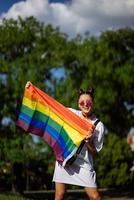 ung kvinna innehav ett HBTQ stolthet flagga i henne händer. foto