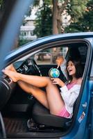 ung kvinna Sammanträde i en bil och innehav en klot foto