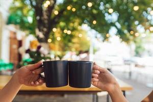 närbild bild av en människor klirr kaffe koppar tillsammans i Kafé foto