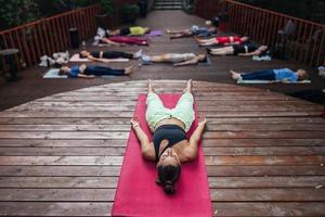 grupp av ung sportig människor praktiserande yoga lektion med instruktör, foto