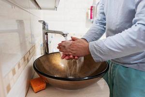 man tvättning händer på brun glas hand tvätta handfat med krom vatten knacka. foto