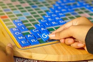 asiatisk hög skola studenter är tävlande i en korsord eller scrabble spel, ett engelsk ord pussel spel. den är en spel den där främjar engelsk inlärning och kritisk tänkande Kompetens. foto