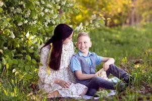 mamma kramar henne liten son , vem är innehav en bukett av liljor av de dal i hans händer foto