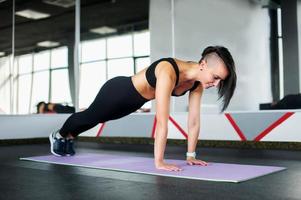 en flicka i de Gym gör yoga och kondition på en Gym matta foto